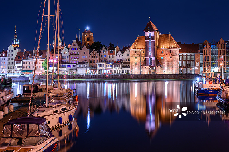 波兰格但斯克夜晚，莫特拉瓦河上灯火辉煌的历史建筑和船只的গুলির全景视图。图片素材
