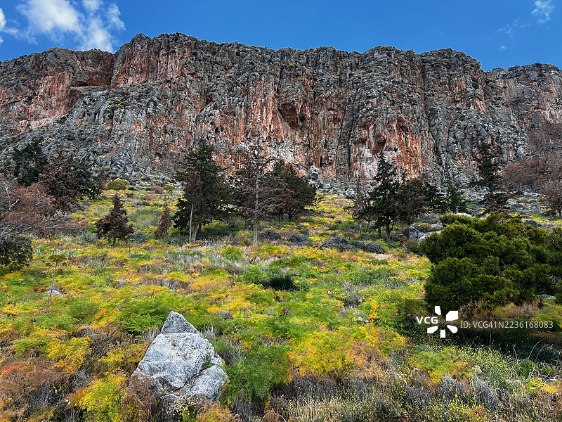 戏剧性的落基山脉风景，郁郁葱葱的绿色和黄色植物在蓝天之下，希腊莫尼姆瓦西亚图片素材