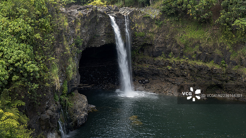 雄伟的瀑布倾泻入宁静的池塘，位于郁郁葱葱的热带森林中，夏威夷希洛，美国图片素材