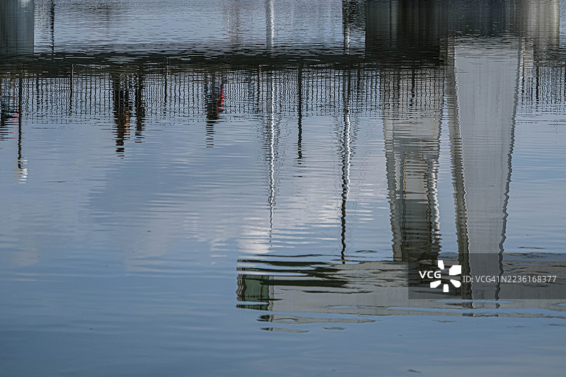 水面波纹上围栏和建筑物的抽象倒影图片素材
