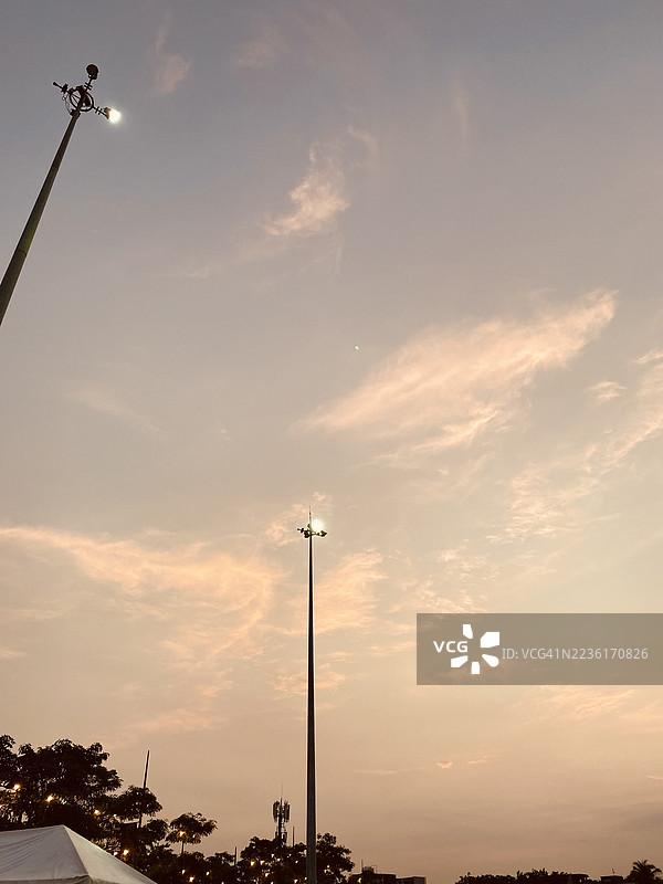 低角度视图的街灯照亮了美丽的日落天空，伴有轻柔的云朵。图片素材
