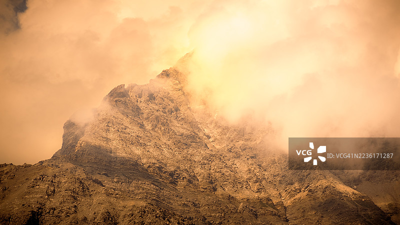 日落时分，云雾缭绕的戏剧性山峰，唤起神秘与宏伟的感觉图片素材