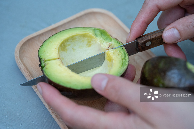 切割鳄梨果实的手部特写镜头。图片素材