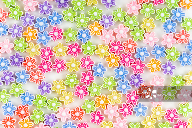 各种颜色的花形珠子在白色背景上。图片素材