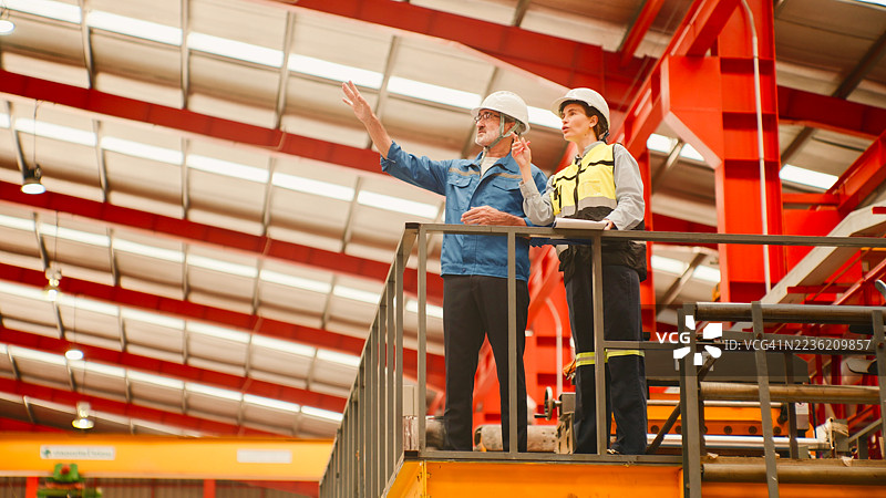 穿着防护装备的工业工人俯瞰制造设施中的生产过程。图片素材