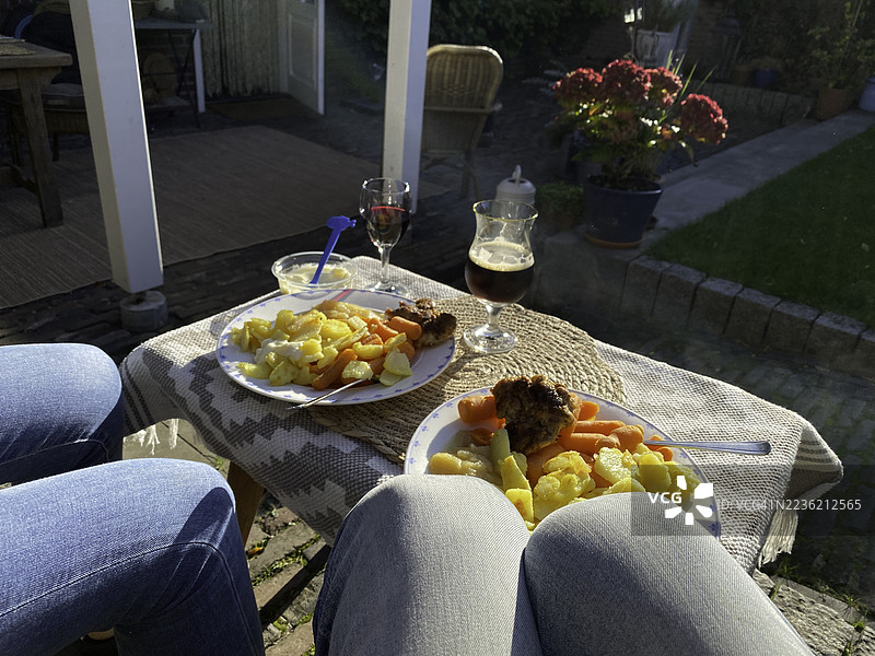 一对情侣在户外厨房享用晚餐。图片素材