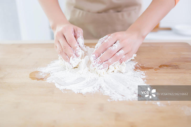 双手在木板上揉面粉，为烘焙准备。图片素材