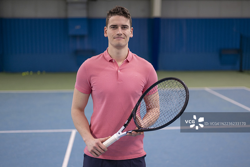 年轻的白人男性网球运动员在室内球场上握着球拍图片素材