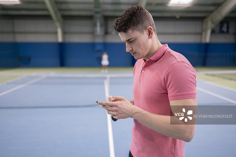 年轻的白人男性网球运动员使用智能手机图片素材