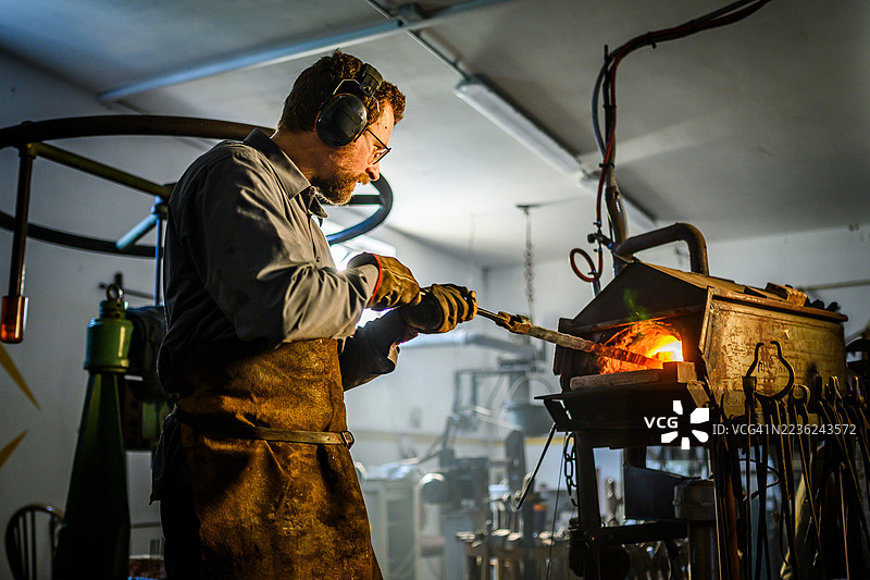 白人工匠在传统铁匠铺中操作金属图片素材
