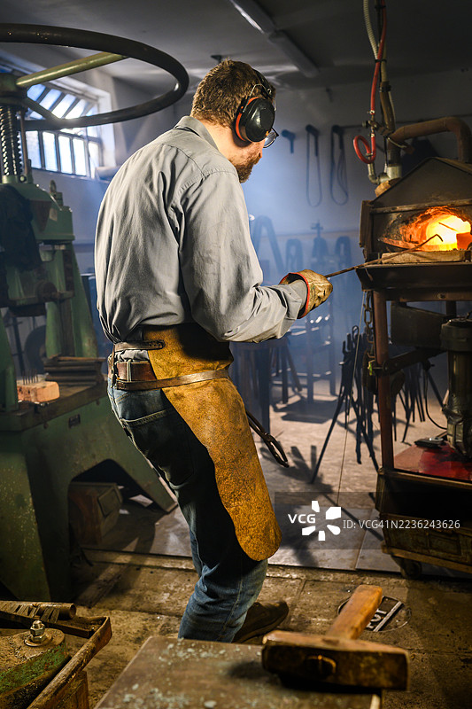 中年黑smith在传统铁匠铺中精通金属加工图片素材