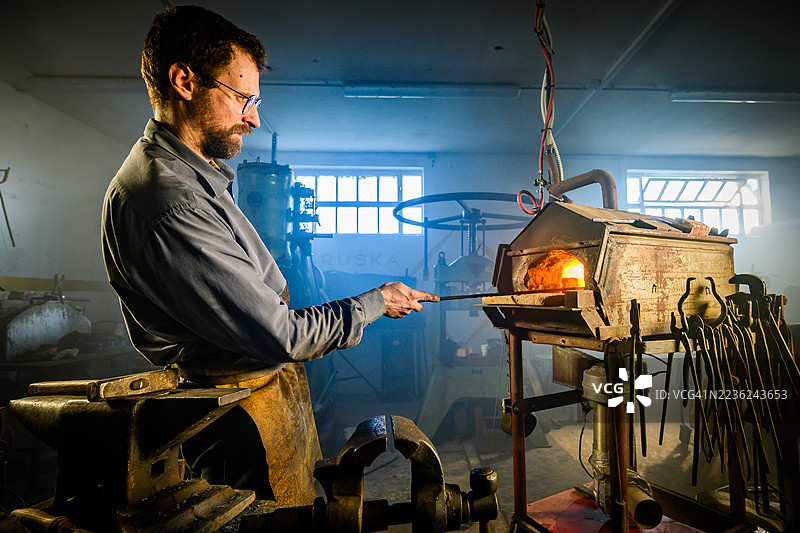 白人铁匠在锻造车间加热金属图片素材