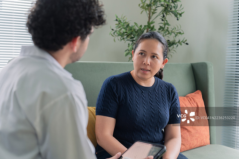 一位拉丁裔男医生在现代诊室里与一位东南亚裔女患者进行咨询图片素材