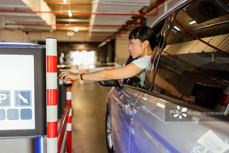 亚洲女性在停车场操作自动门机图片素材