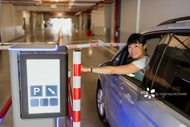 女性司机在地下车库与停车机器互动图片素材