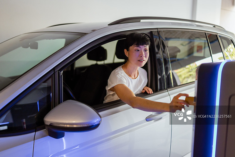 日本女性伸出车窗用信用卡支付停车费图片素材