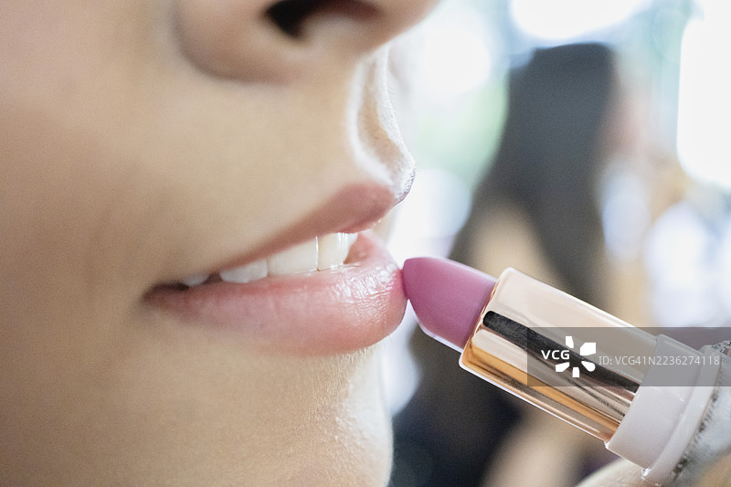 年轻女性涂抹粉色口红图片素材