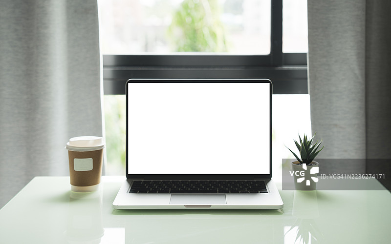 咖啡馆背景下桌子上的笔记本电脑空白屏幕。咖啡店桌子上的笔记本电脑空白屏幕，背景模糊。图片素材