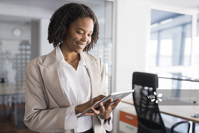一位非裔美国女商人在办公室里微笑着使用平板电脑图片素材