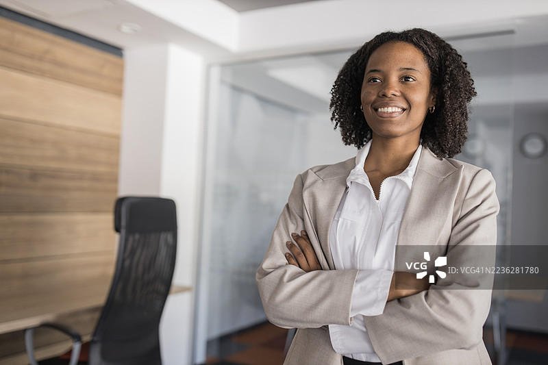 自信的女商人在现代办公室里双臂交叉而笑图片素材