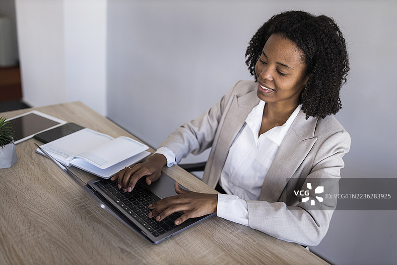 现代办公室里，一位黑人女商人在笔记本电脑上打字。图片素材