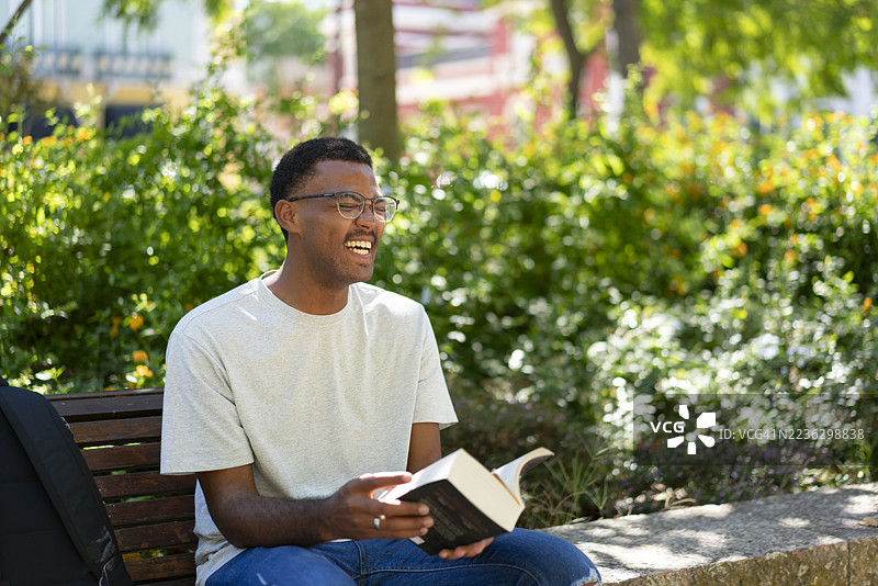 非洲少年在公园里阅读一本书图片素材