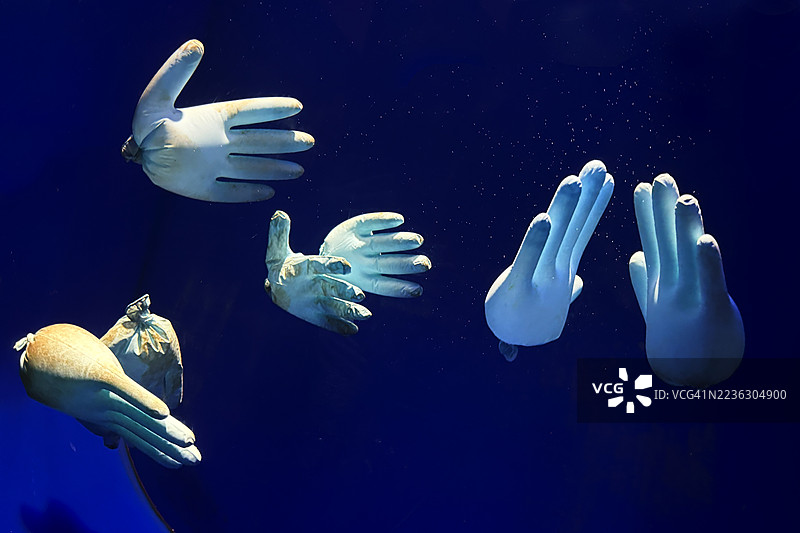 漂浮在海上的乳胶手套，象征着污染图片素材