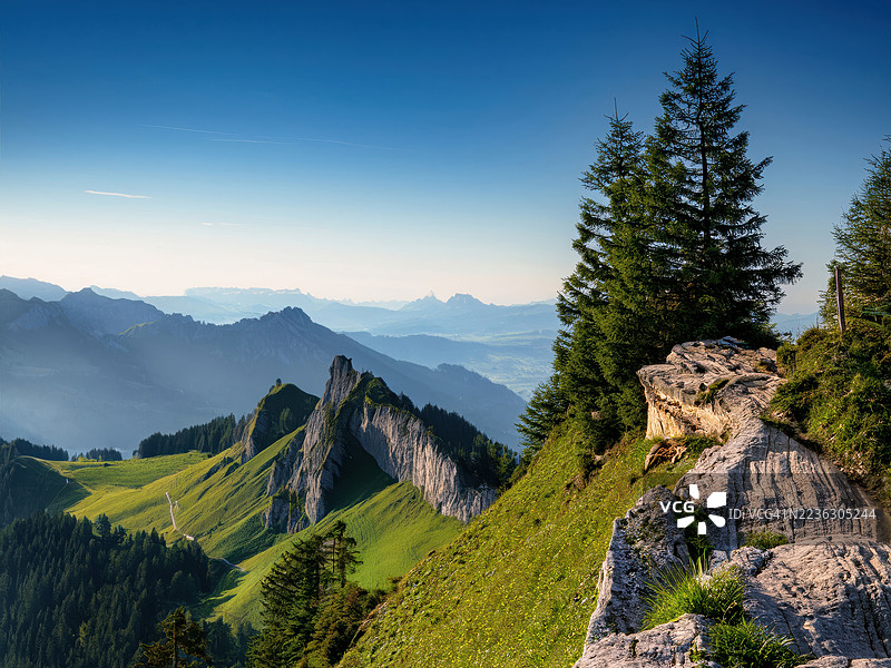 雄伟的山脉，绿意盎然的山坡和高耸的树木在晴朗的蓝天下，唤起宁静与自然之美的感觉，阿罗萨，瑞士图片素材
