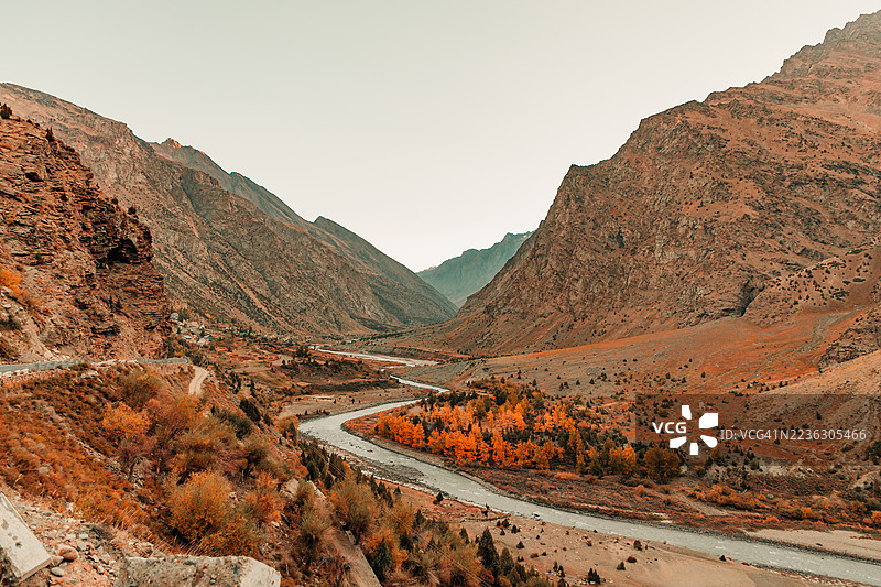 一条蜿蜒的河流穿过广阔的山谷，秋天的树叶在晴朗的天空下绽放，地点：印度基斯帕。图片素材