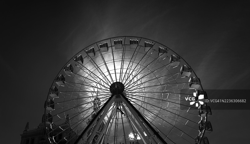 低角度视图的摩天轮在夜空中剪影，营造出戏剧性和标志性的城市景观图片素材