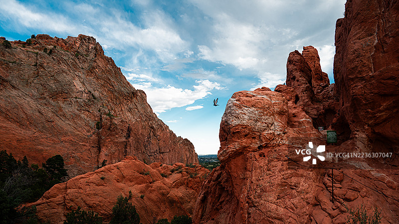 壮丽的红色岩石在生动的蓝天下，飞翔的鸟儿展现了大自然的宏伟。图片素材