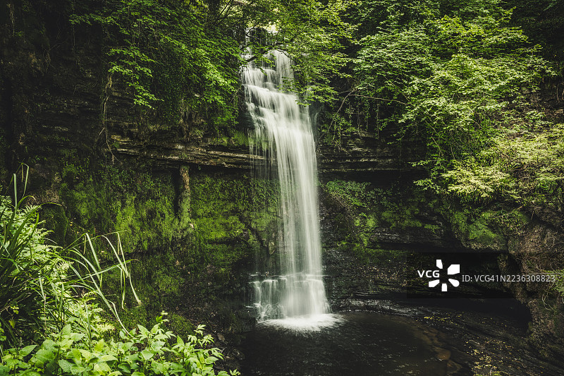 壮观的瀑布倾泻而下，穿过郁郁葱葱的森林，格伦卡尔，爱尔兰图片素材