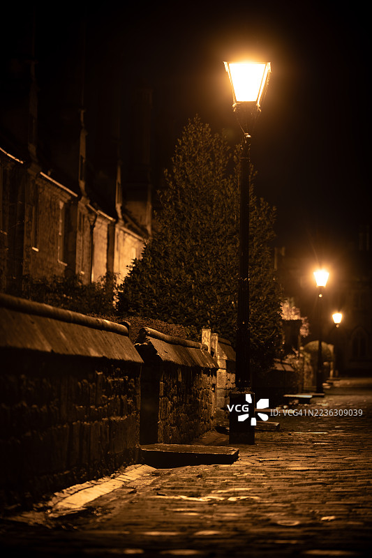 夜晚的街道被复古路灯照亮，古老建筑环绕，威尔斯，英国图片素材