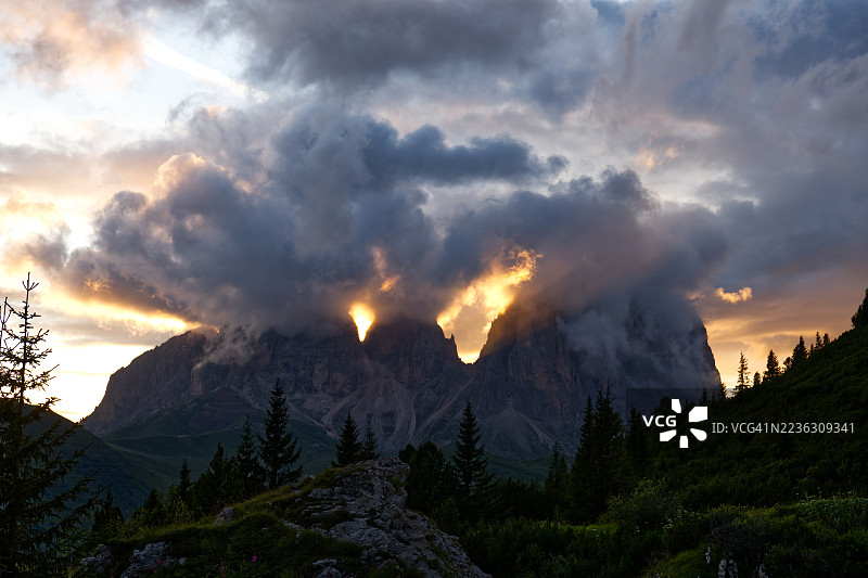 壮丽的日落映照在山峰上，五彩斑斓的云彩与郁郁葱葱的森林相映成趣图片素材