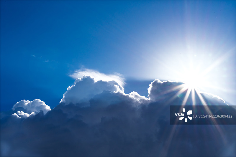 从低角度看，明亮的阳光透过戏剧性的云层洒在生动的蓝天上，营造出一种光辉而充满希望的氛围，德国阿沙芬堡。图片素材