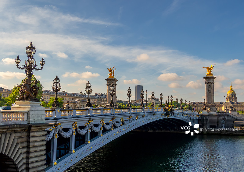 法国巴黎，亚历山大三世桥横跨塞纳河，背景是荣军院的穹顶，天空湛蓝图片素材