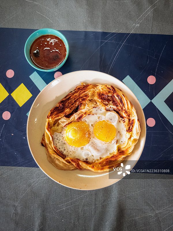 高角度视图的美味早餐，桌上摆放着煎蛋和印度薄饼，旁边配有咖喱。图片素材