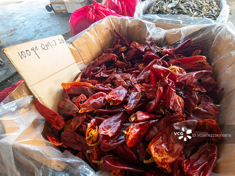 市场摊位上高角度拍摄的干辣椒，价格标签清晰可见，展现出鲜艳的红色和质朴的纹理。图片素材