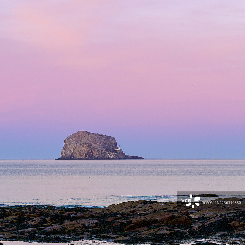 巴斯岩岛和灯塔在海上绚丽日落天空下的戏剧性风景，英国图片素材