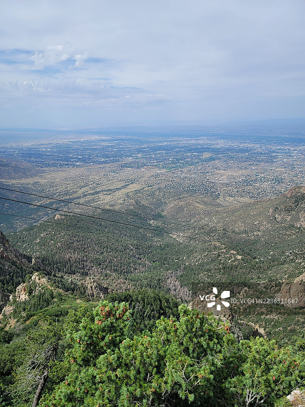 高角度俯瞰广阔的城市和山脉景观，云层覆盖下展现城市扩张与自然美景，伯纳利洛县，美国，USA图片素材