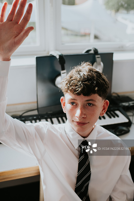 一位年轻男子礼貌地举手向老师提问图片素材