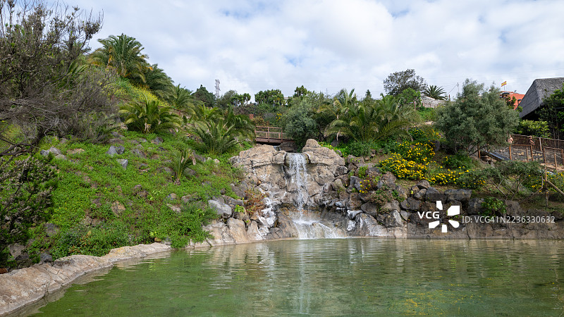 热带公园中人工瀑布倾泻入池塘图片素材