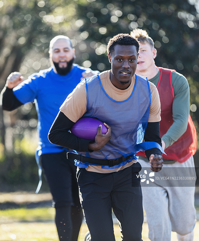 三个男人在公园里踢旗帜足球图片素材