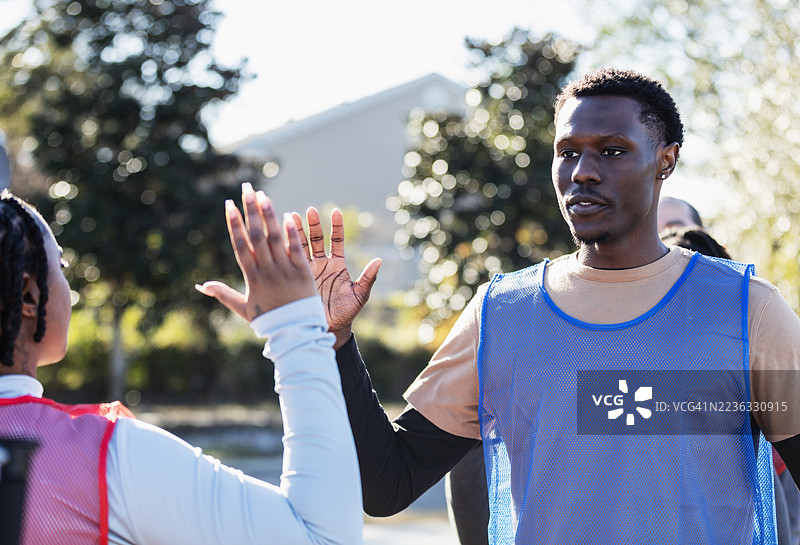男子在公园打团队运动时与对手击掌致意图片素材