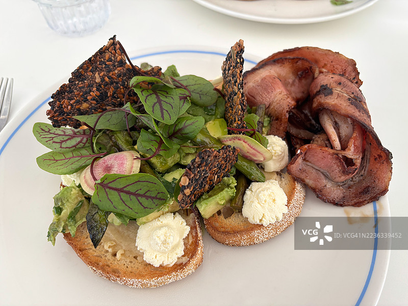 酸面包吐司配牛油果、芦笋、菲达奶酪、红脉酸模、种子脆饼和培根图片素材