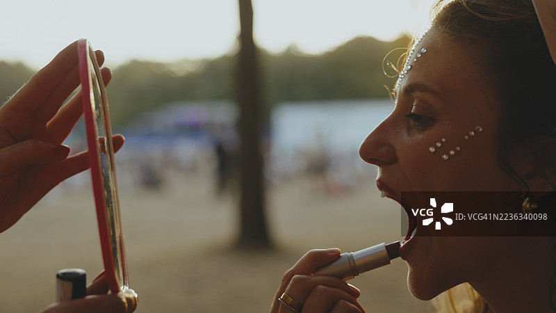 年轻的白人女性在音乐节上涂口红图片素材