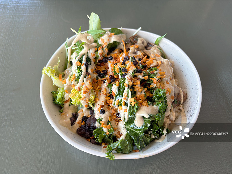 椰子棕米沙拉碗，配有沙拉菜、红豆、胡萝卜、西兰花、羽衣甘蓝、香菇、黑豆、葡萄干、蒜香烤夏威夷果和柠檬芝麻酱。图片素材
