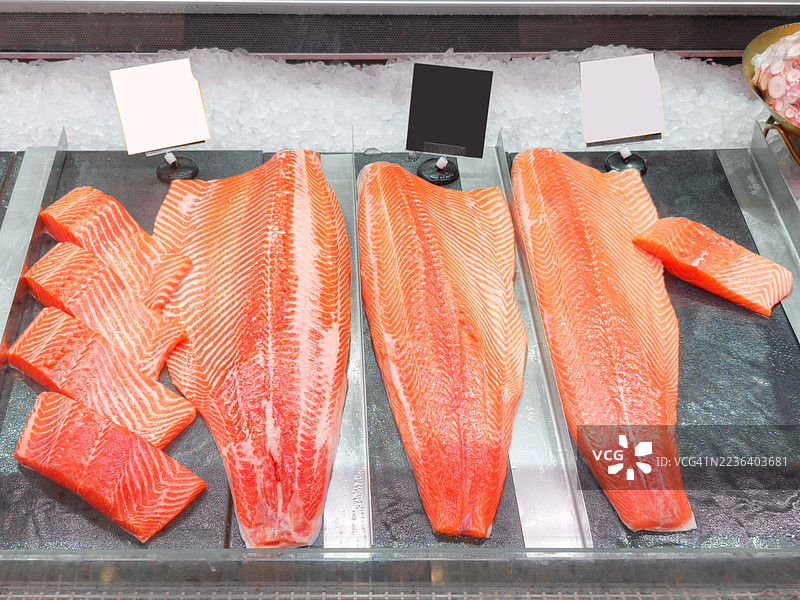海鲜柜台上的新鲜三文鱼片放在冰上图片素材