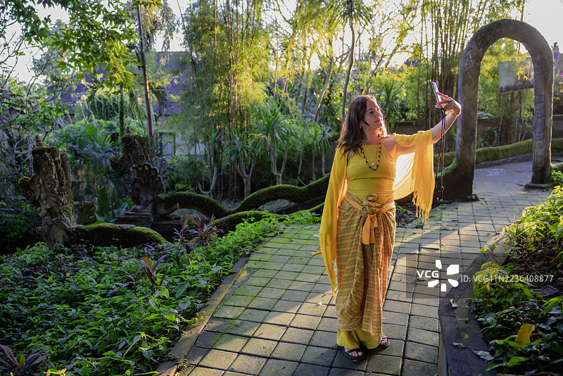 年轻女性在巴厘岛古庙附近自拍肖像图片素材