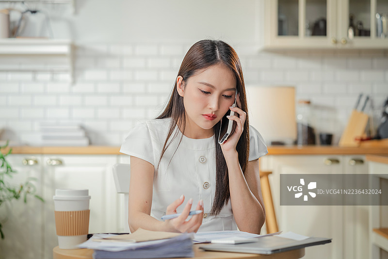 女性企业主在家办公室使用智能手机咨询财务顾问，同时利用人工智能辅助进行财务分析和战略创业规划解决方案。图片素材